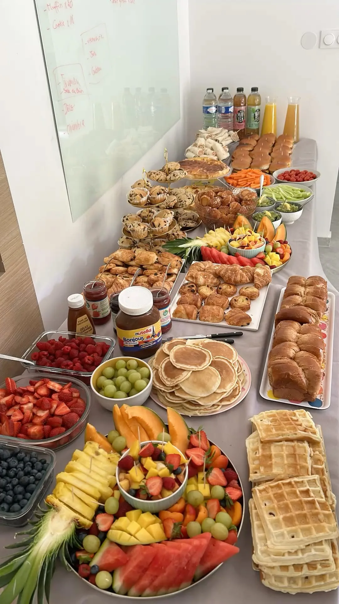 Ein reich gedeckter Tisch mit einem Frühstücksbuffet bestehend aus Waffeln, Pfannkuchen, Obst und verschiedenen Backwaren.