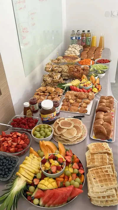 Ein reich gedeckter Tisch mit einem Frühstücksbuffet bestehend aus Waffeln, Pfannkuchen, Obst und verschiedenen Backwaren.